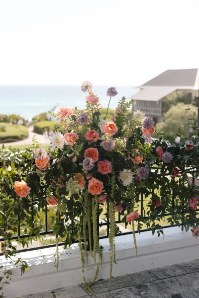 Wedding floral installation featuring garden rose wedding flowers arranged in an airy spray against an ocean and sky backdrop with coastal greenery.