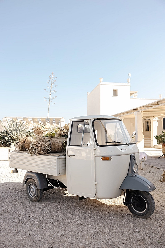 Wedding getaway car, a vintage wedding car three-wheeler truck decorated with wicker baskets of dried florals on a desert patio setting