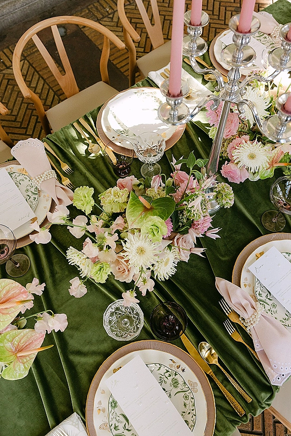 Reception tablescape with green wedding tablescape details, pink taper candles in silver candelabra, floral centerpiece on patterned brick floor