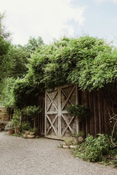 Barn venue entrance at a rustic wedding venue exterior, framed by climbing vines around the doorway.