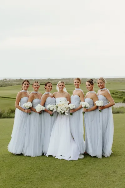 Bridal party portrait featuring dusty blue bridesmaid dresses as they stand with the bride in a balanced, elegant pose