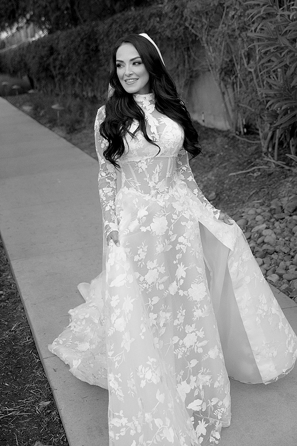 Bridal portrait of a bride in a black and white bridal portrait wearing a long sleeve lace gown and veil on a garden path with trees