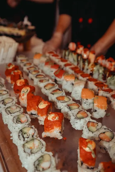 Sushi station at a wedding sushi bar showcasing neat assortments arranged in rows, topped with spicy mayo for a colorful, modern presentation.