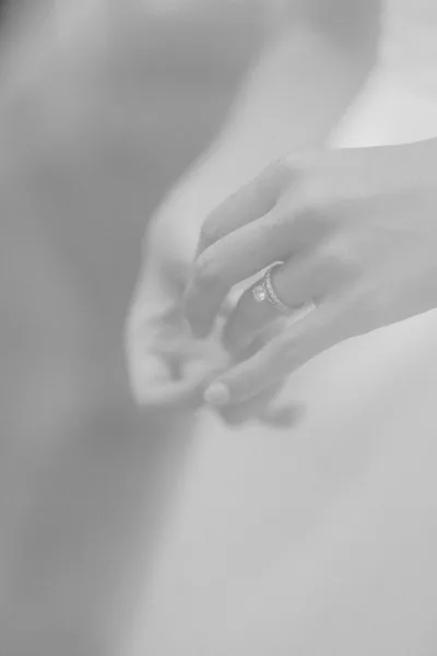 Wedding ring close-up with an engagement ring close up, sparkling diamond on a hand beside a matching band against blurred skin tones