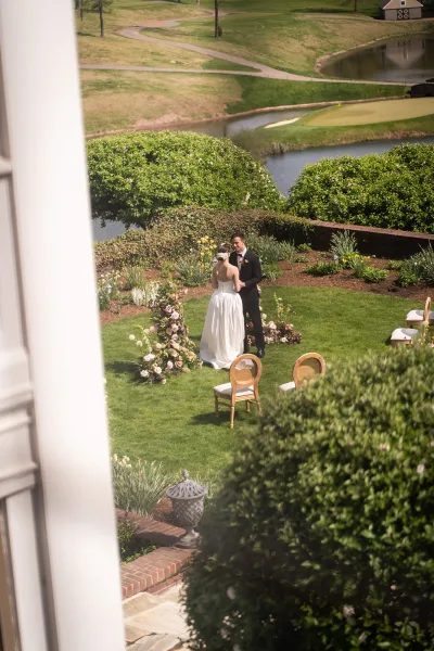 Ceremony moment during an outdoor garden ceremony as the couple exchange vows beside a pond, framed by blush ceremony flowers.