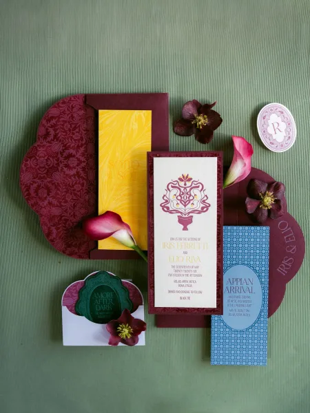 Wedding invitation suite featuring burgundy wedding invitations on a green textured fabric backdrop, styled with calla lilies.