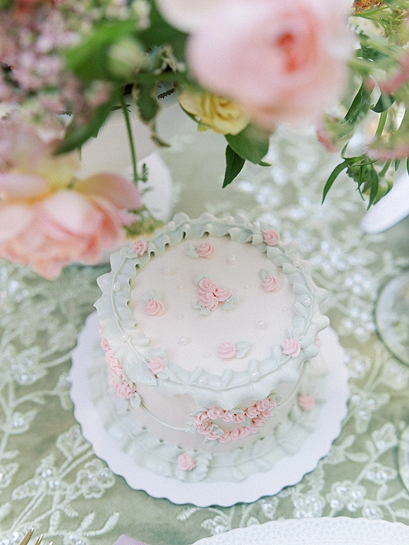 Wedding cake with vintage wedding cake buttercream rosettes, ruffled icing and pearl sugar beads on a lace tablecloth reception table