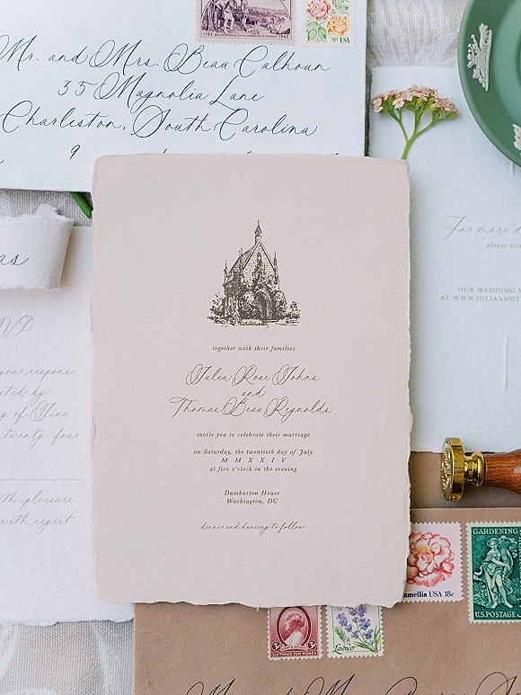 Wedding invitation suite with deckle edge wedding invitation, calligraphy envelope, wax seal, and stamps styled on linen with layered cards