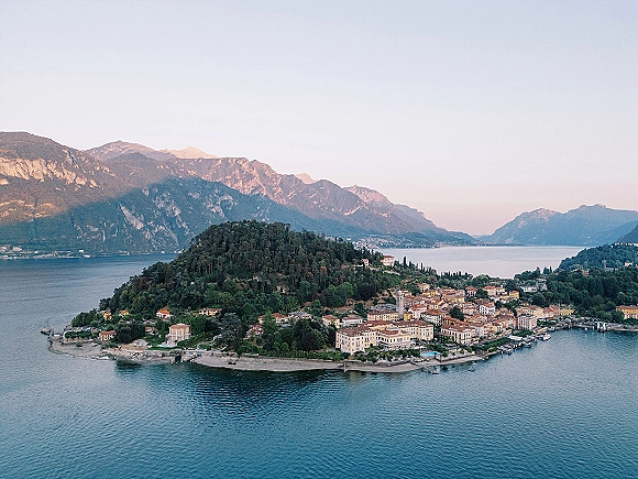 Wedding venue landscape with an aerial wedding venue view of a waterfront town with boats and a church tower on a lake with mountains beyond