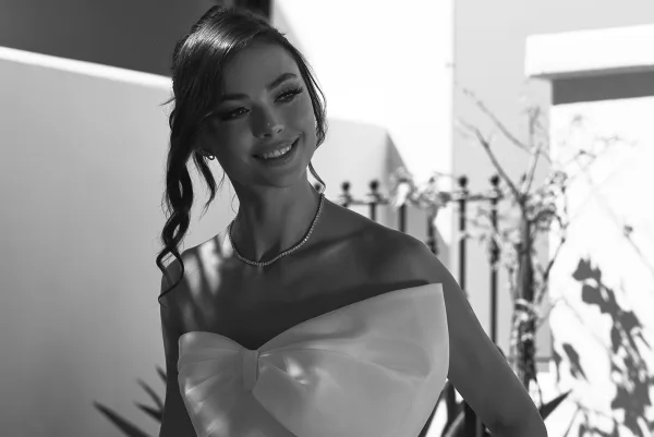 Bridal portrait in black and white of a bride in a strapless bow bodice gown, wearing a tennis necklace on a sunlit modern terrace with shadows