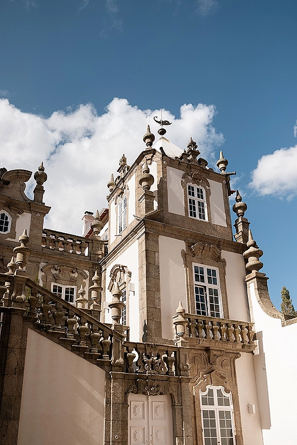 Wedding venue exterior of a historic wedding venue with ornate stone balustrade, grand staircase, and tall windows under blue sky clouds