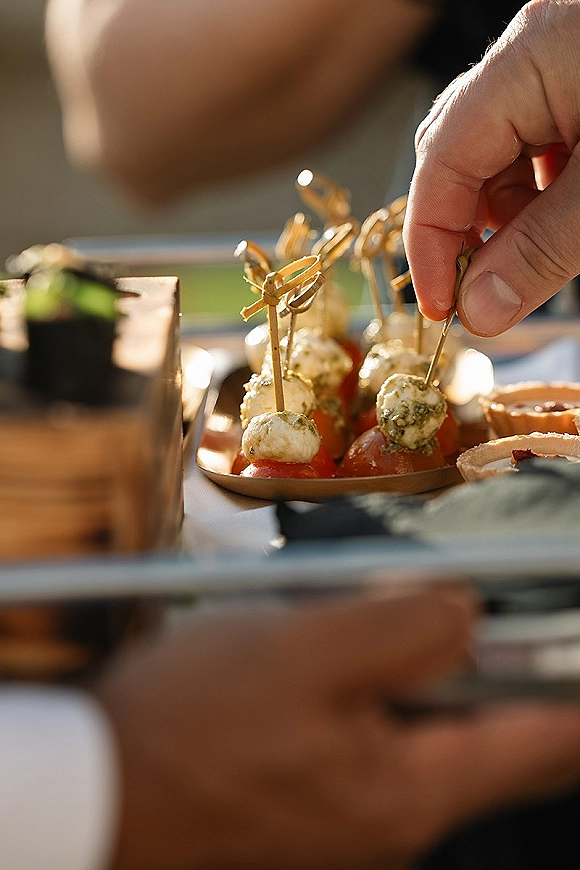 Cocktail appetizers arranged as wedding cocktail hour appetizers with cheese balls and cherry tomatoes on skewers, served outdoors on a platter