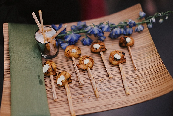Wedding cocktail hour appetizers with passed hors d'oeuvres on a wood serving board, featuring skewers, grilled bites, breadsticks, and white dipping sauce