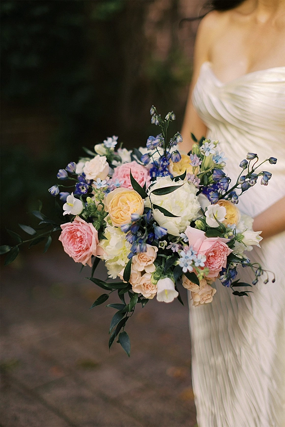 Bridal bouquet in a bride’s hands, garden style bridal bouquet with blush roses, hydrangea, blue blooms and greenery on a blurred garden path