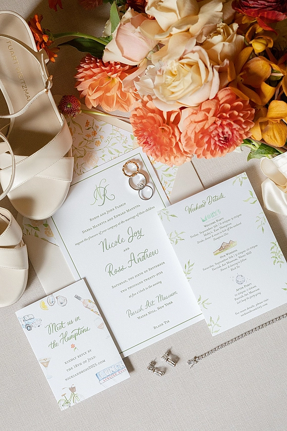 Invitation suite wedding invitation flat lay with RSVP and itinerary cards, rings, earrings, rhinestone bracelet, shoes, and bouquet on linen