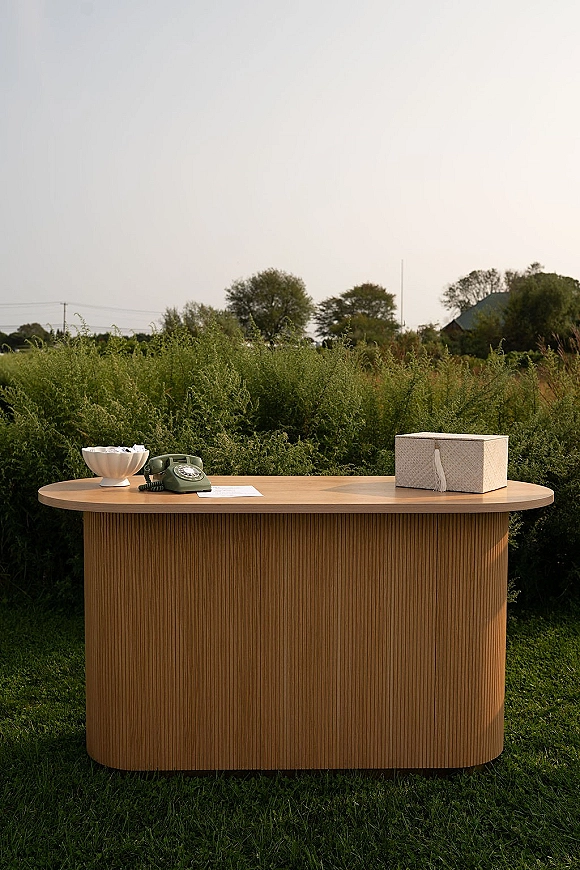 Welcome table styled with a wedding welcome table setup on a wood table, featuring a rotary telephone, cards, and tassel box on a lawn