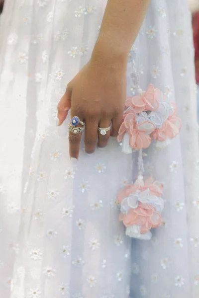 Wedding ring close-up of a bride’s hand showing an engagement ring close up with stacked bands, pastel corsage, and tulle backdrop
