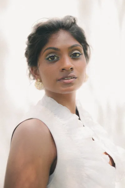 Bridal portrait close up bride portrait in soft window light, wearing gold earrings with an updo and sleeveless wedding dress against neutral backdrop