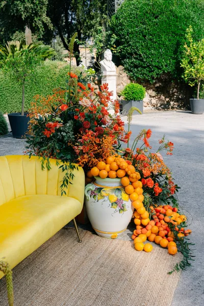 Wedding lounge decor featuring citrus fruit in an outdoor reception lounge framed by garden hedges and a stone wall