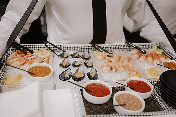 Seafood station wedding raw bar with shrimp, crab legs and mussels on an ice bed, lemon wedges and sauces on a buffet table
