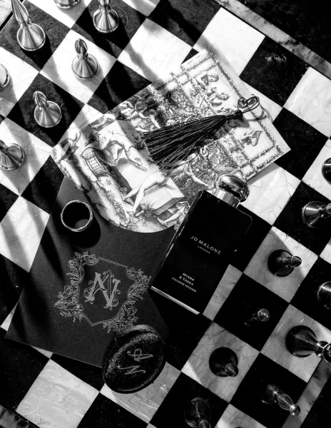 Invitation suite featuring a black wedding invitation, styled with chess pieces atop a bold chessboard pattern background.