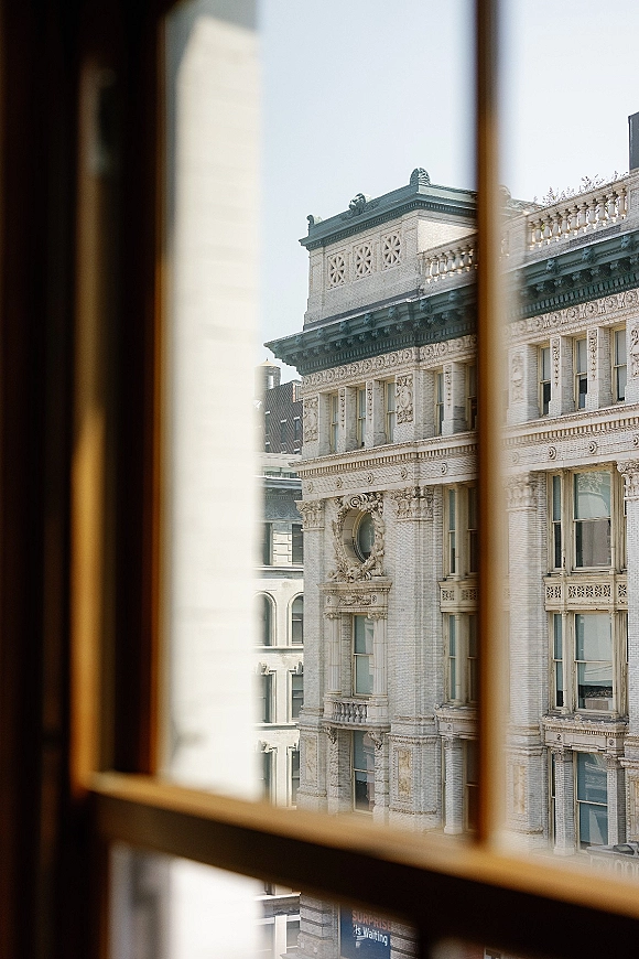Wedding venue exterior with a window frame accent, showing a historic building facade against city buildings and open sky
