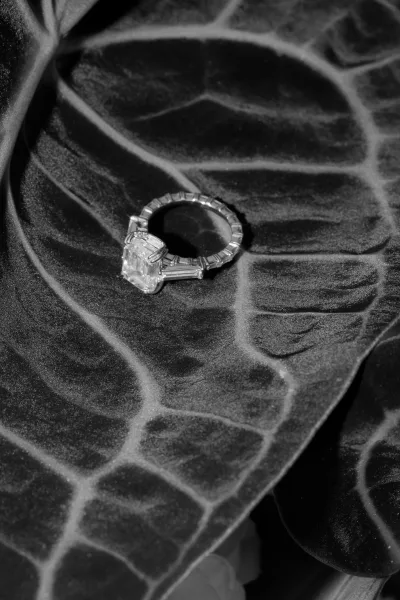 Engagement ring, an emerald cut engagement ring resting on a tropical leaf with rich foliage texture.