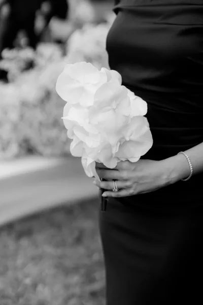 Bouquet close-up of an orchid bouquet, an engagement ring glinting in soft light against blurred garden foliage.