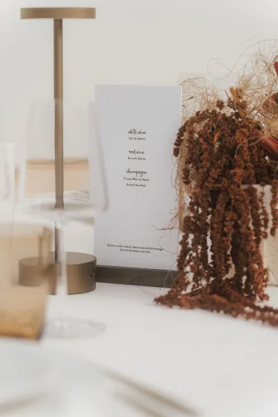 Wedding drink menu displayed as a wine list sign, styled beside dried florals with minimalist design and modern typography.