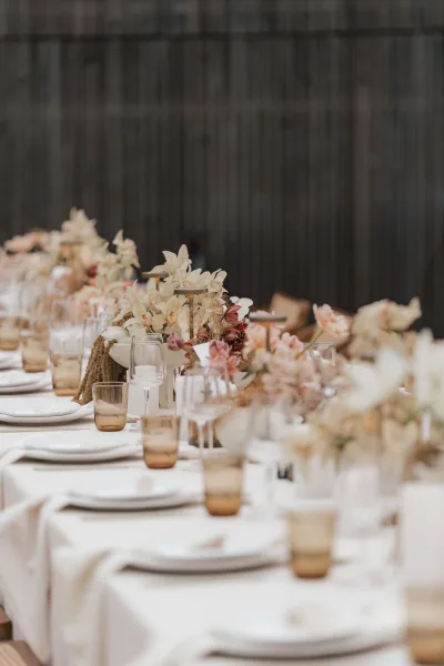 Reception tablescape for a neutral wedding table with soft candlelight, set against a warm wood wall.