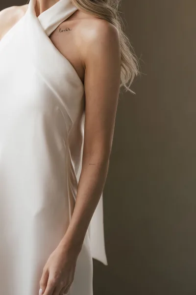 Wedding dress detail highlights a halter wedding dress as the bride’s wedding ring catches the light, her hand resting gently along the smooth bodice.