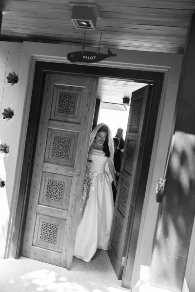 Bridal entrance as the bride walking in through double doors, veil flowing over a strapless dress, holding a bouquet in an indoor entryway