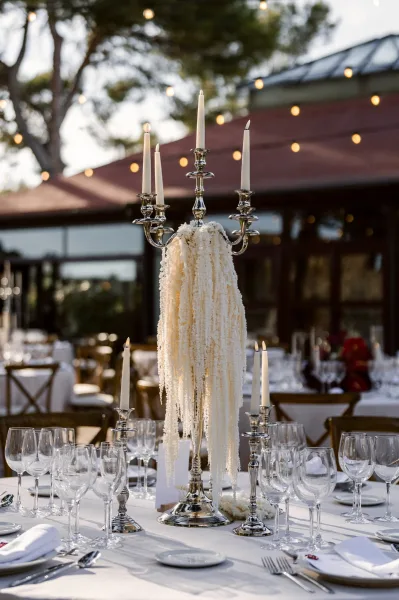 Wedding centerpiece, a candelabra centerpiece, crowns a formal table, framed by trees, a building exterior, and open sky.