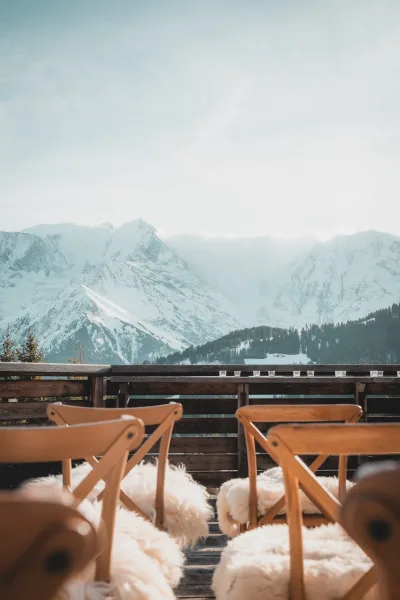Mountain ceremony setup with outdoor wedding ceremony seating, wood chairs with sheepskin covers and tea lights on a deck facing snowy peaks
