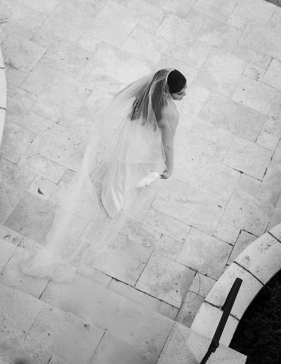 Bridal portrait, overhead bridal photo of a bride in a strapless dress with long veil and train flowing over stone steps in black and white