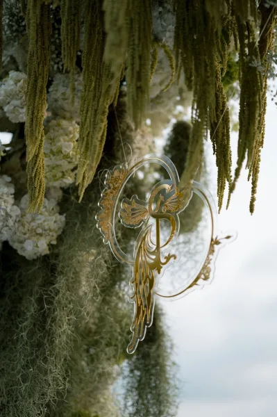 Wedding monogram sign, an acrylic wedding sign suspended with hanging amaranthus, appearing weightless against the open sky backdrop.