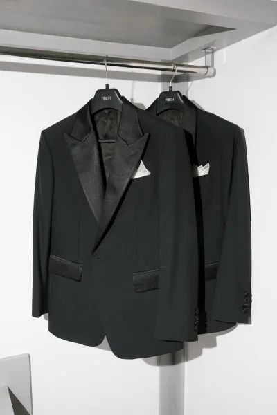 Wedding tuxedo, a black tuxedo jacket with a crisp white pocket square, presented with clean lines and minimal styling for an elegant look.
