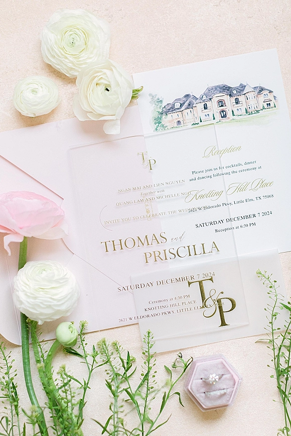 Invitation suite wedding invitation flat lay with vellum wrap, gold foil monogram, venue card, RSVP, ring box and ranunculus on linen backdrop