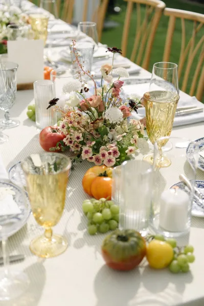 Reception tablescape for an outdoor wedding table, featuring amber goblets and refined place settings arranged for an elegant, convivial feast.