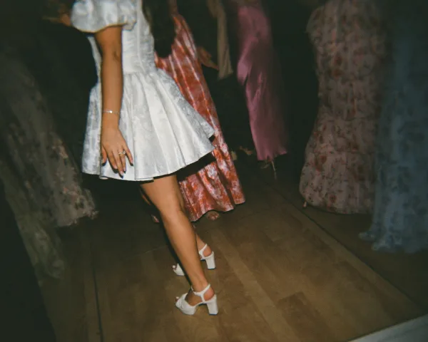Short wedding dress styled as a chic bridal mini dress with puff sleeves on a wood dance floor in a dark room