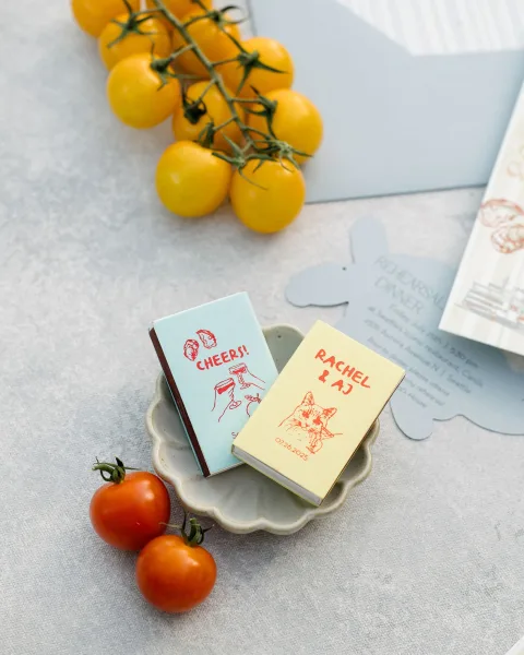 Wedding matchbooks presented as personalized wedding favors, neatly stacked in a ceramic dish for guests to take