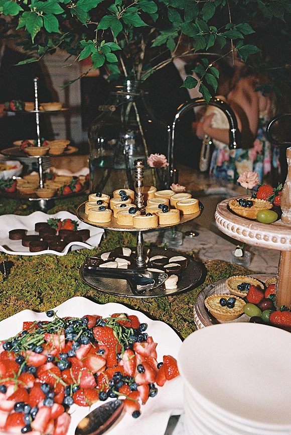 Wedding dessert table with dessert table ideas, mini tarts, cheesecakes and truffles on stands, plus berry platters and moss runner at indoor reception
