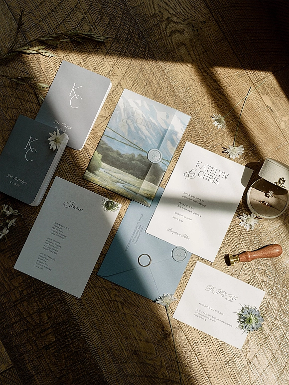 Invitation suite wedding invitation suite flat lay with wax seal and blue envelope, rings and dried flowers on a wood table in window light