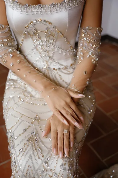 Wedding dress close-up of a beaded wedding dress, with sheer bridal gloves gently resting over the bodice, drawing attention to the ornate beading.
