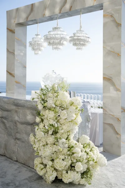 Wedding bar setup for an outdoor cocktail bar, framed by a marble arch on an ocean-view terrace under open sky.