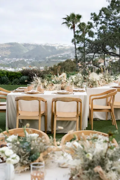 Reception tablescape showcasing outdoor reception decor with pampas grass accents on a lawn set against mountains and palm trees.