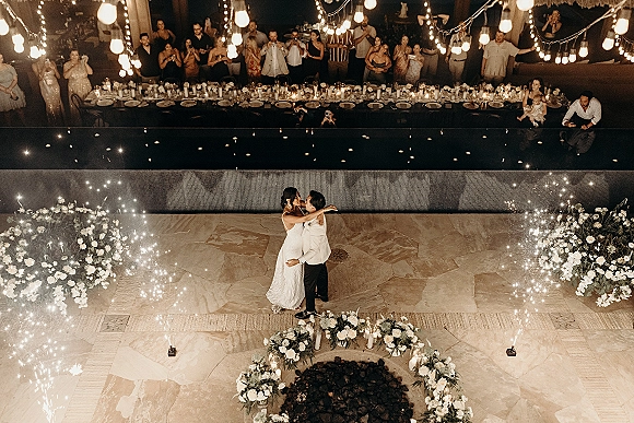 First dance with wedding first dance sparklers as sparkler fountains flare around the couple on a poolside stone patio at night under string lights