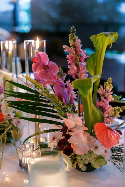 Wedding centerpiece of tropical wedding flowers with cascading orchids arranged across the tabletop.