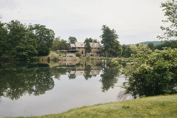 Lakeside wedding venue and waterfront wedding venue with a stone manor house beside a calm lake and distant wooded hills.