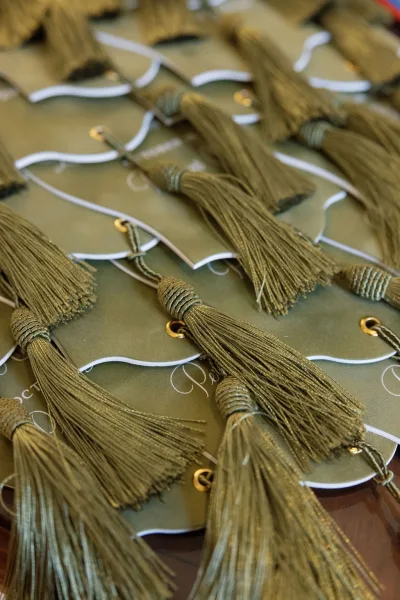 Wedding place cards with tassel place cards details, olive green cardstock tags tied with string, gold grommets and calligraphy on a tabletop